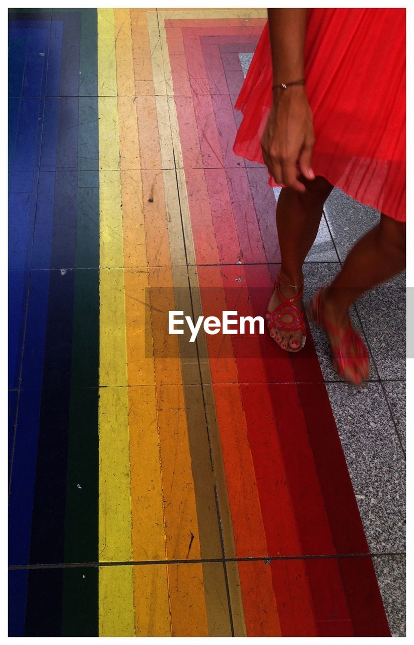 Low section of woman wearing dress standing on multi colored tiled floor