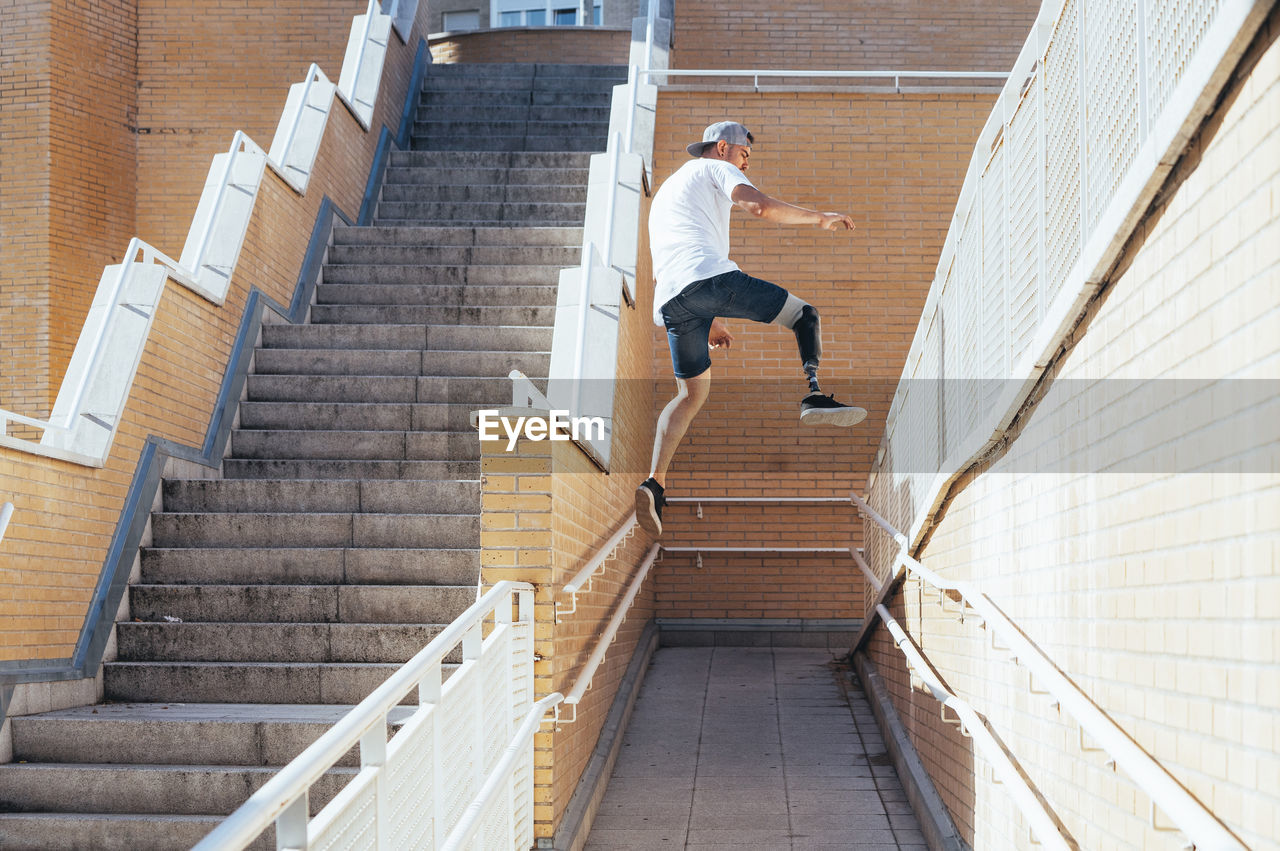 Young man with leg prosthesis performing parkour in the city