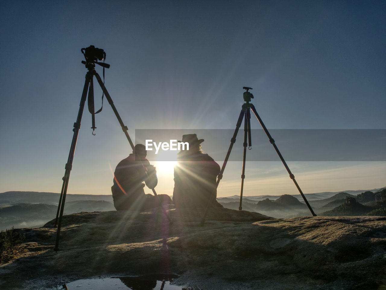 Creative artists stay at own cameras on tripods. photo enthusiasts work together on cliff