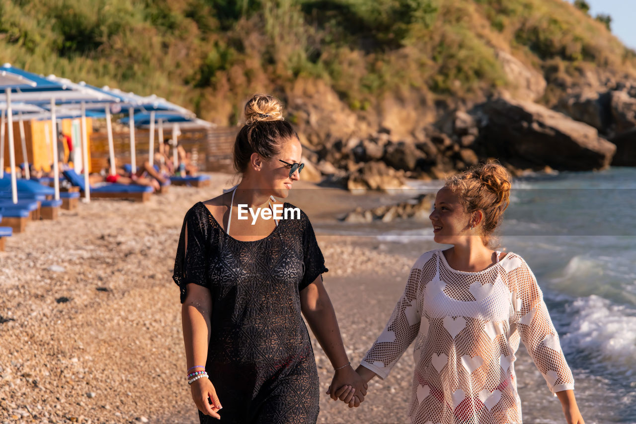 Portrait of smiling friends standing at beach