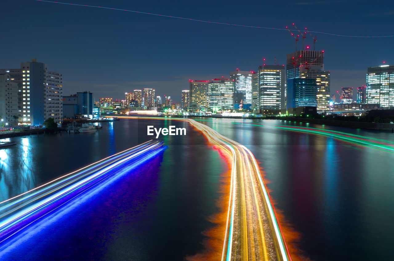 Illuminated light trails amidst buildings in city at night