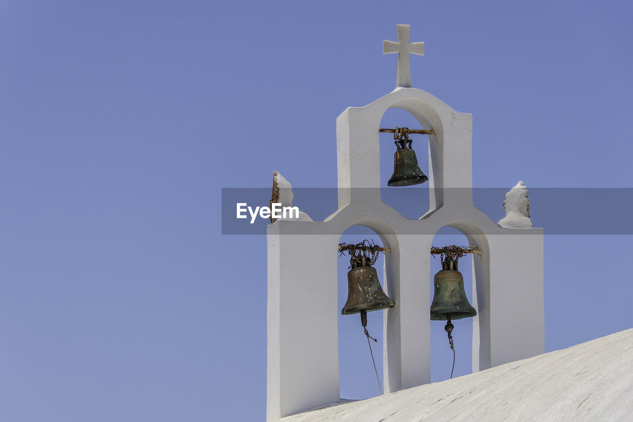Santorini, greece, may 3, 2024. three bells of an orthodox church with a blue sky