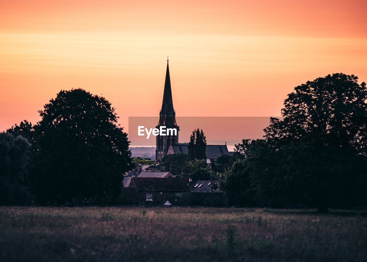 Silhouette trees and buildings against sky at sunset