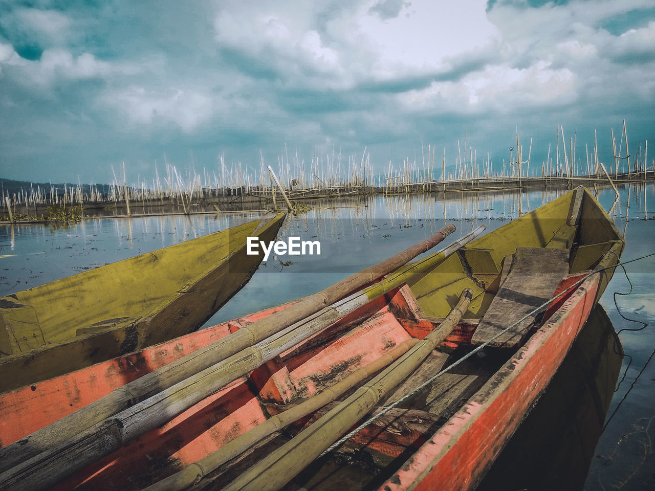 PANORAMIC VIEW OF FISHING BOATS MOORED AT LAKE AGAINST SKY