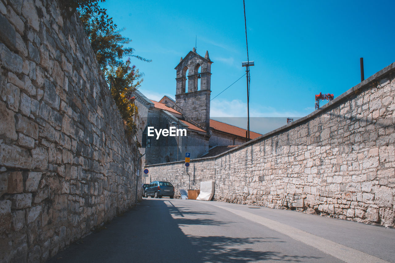 STREET AMIDST BUILDINGS AGAINST SKY IN CITY