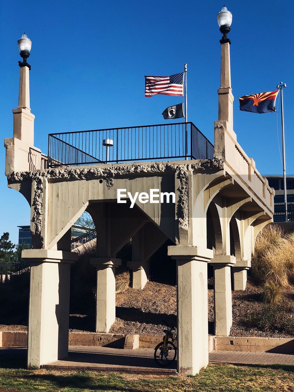 Low angle view of flags on bridge against blue sky