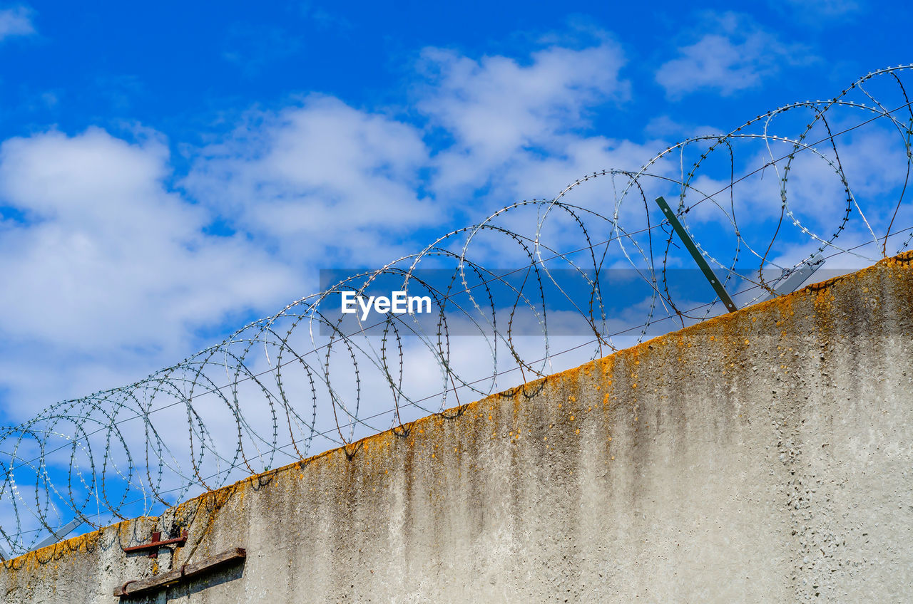 Barbed wire fence on high wall. protection of important object.
