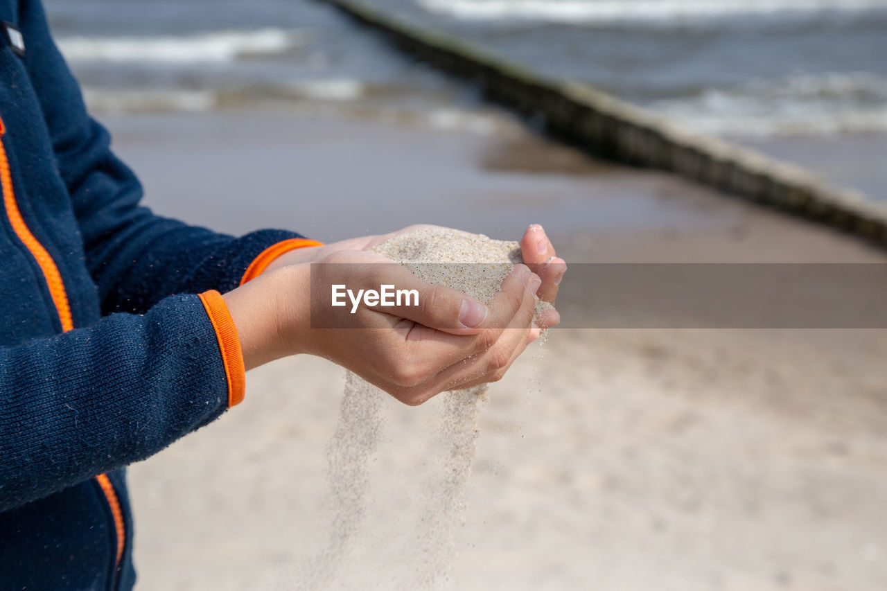 Midsection of person holding sand at beach