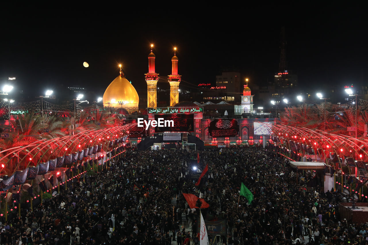 crowd, night, architecture, group of people, illuminated, audience, event, celebration, built structure, building exterior, large group of people, concert, performance, city, red, outdoors, lighting equipment, arts culture and entertainment, high angle view, travel destinations, sports