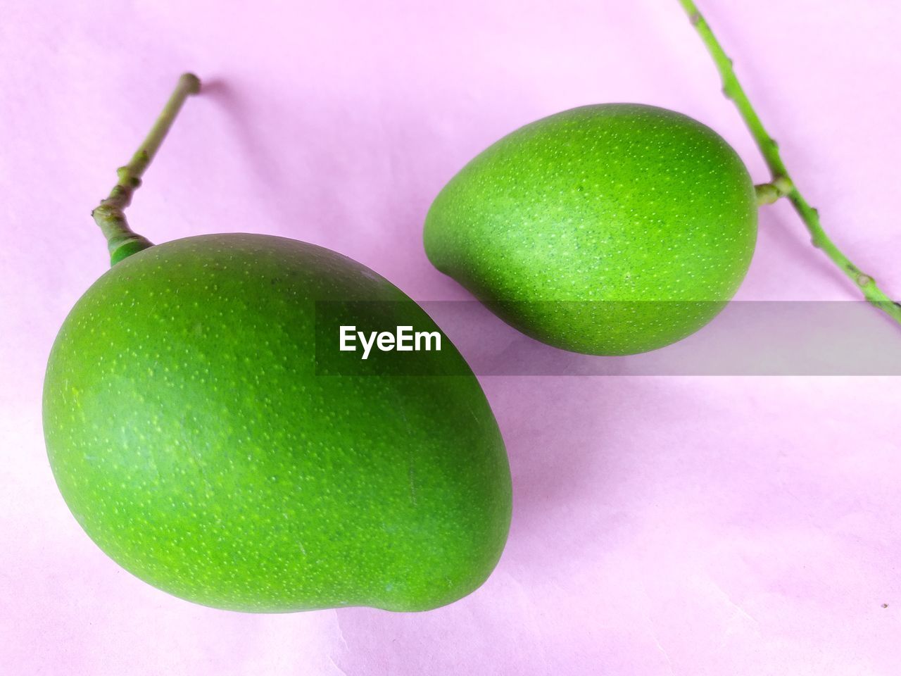 CLOSE-UP OF GREEN FRUIT ON TABLE AGAINST WHITE BACKGROUND