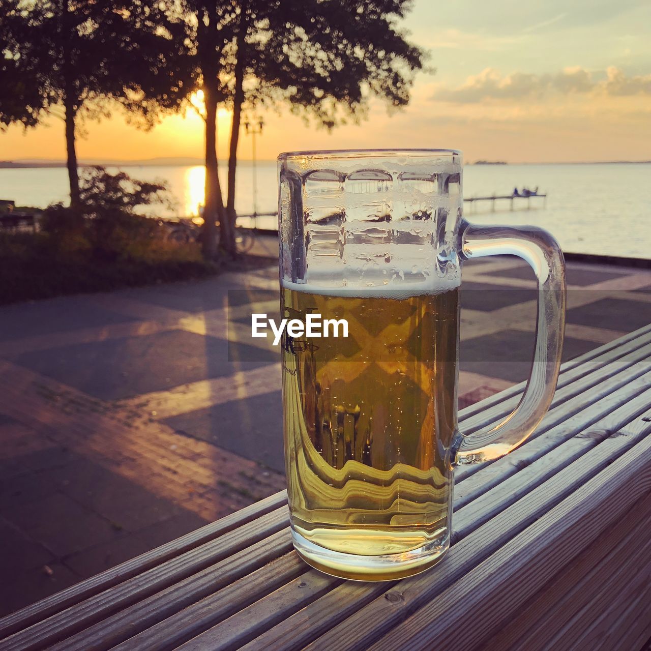 Beer glass on table against sea during sunset