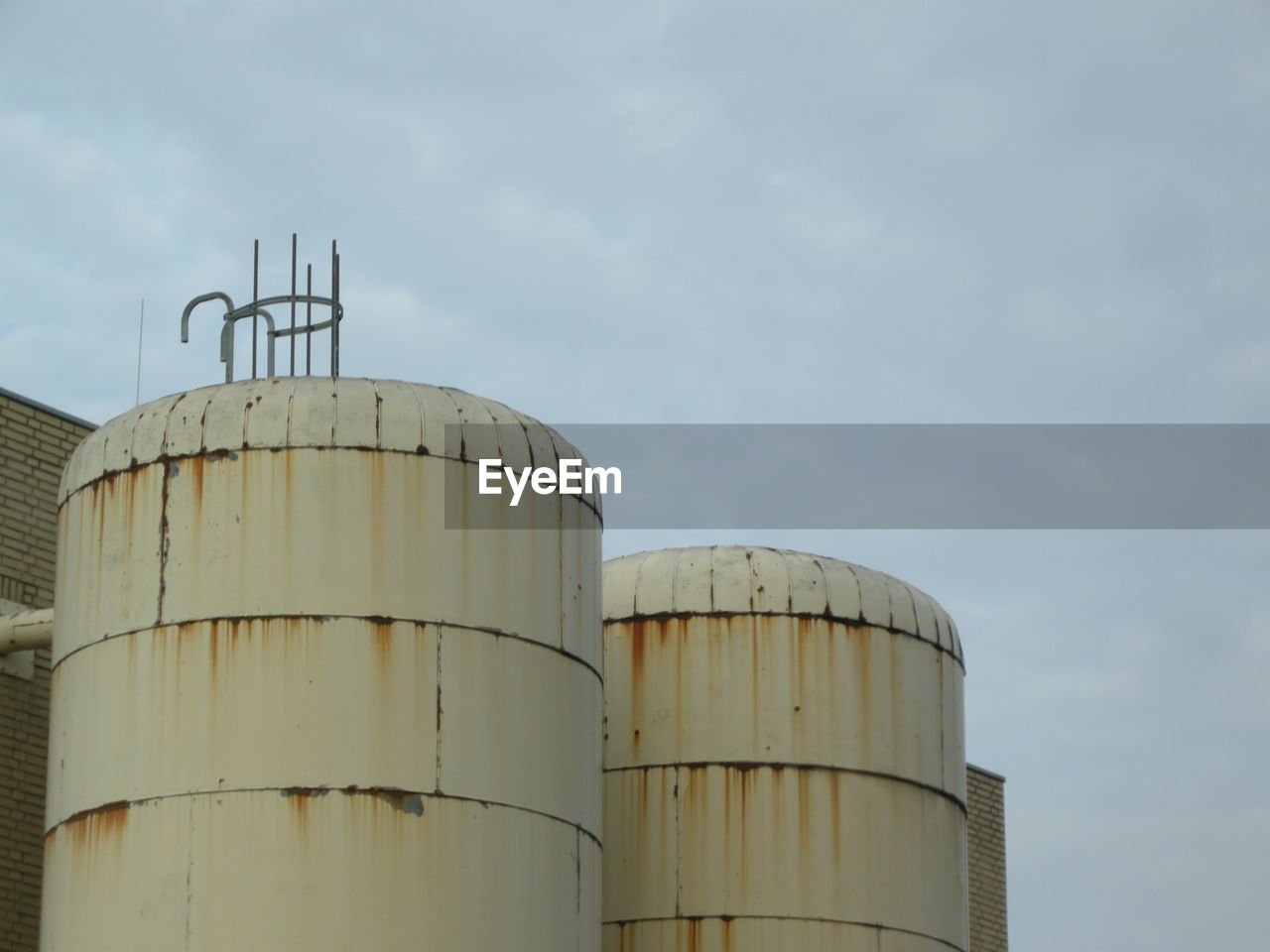 Low angle view of industry against cloudy sky