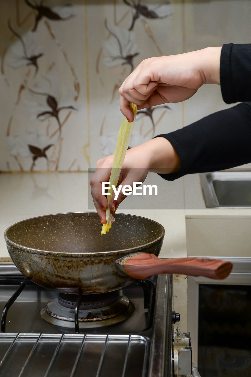 Cropped hand of person preparing food in kitchen