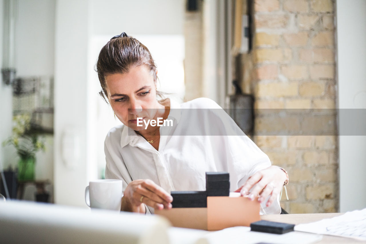 Female design professional working with boxes while sitting at home office