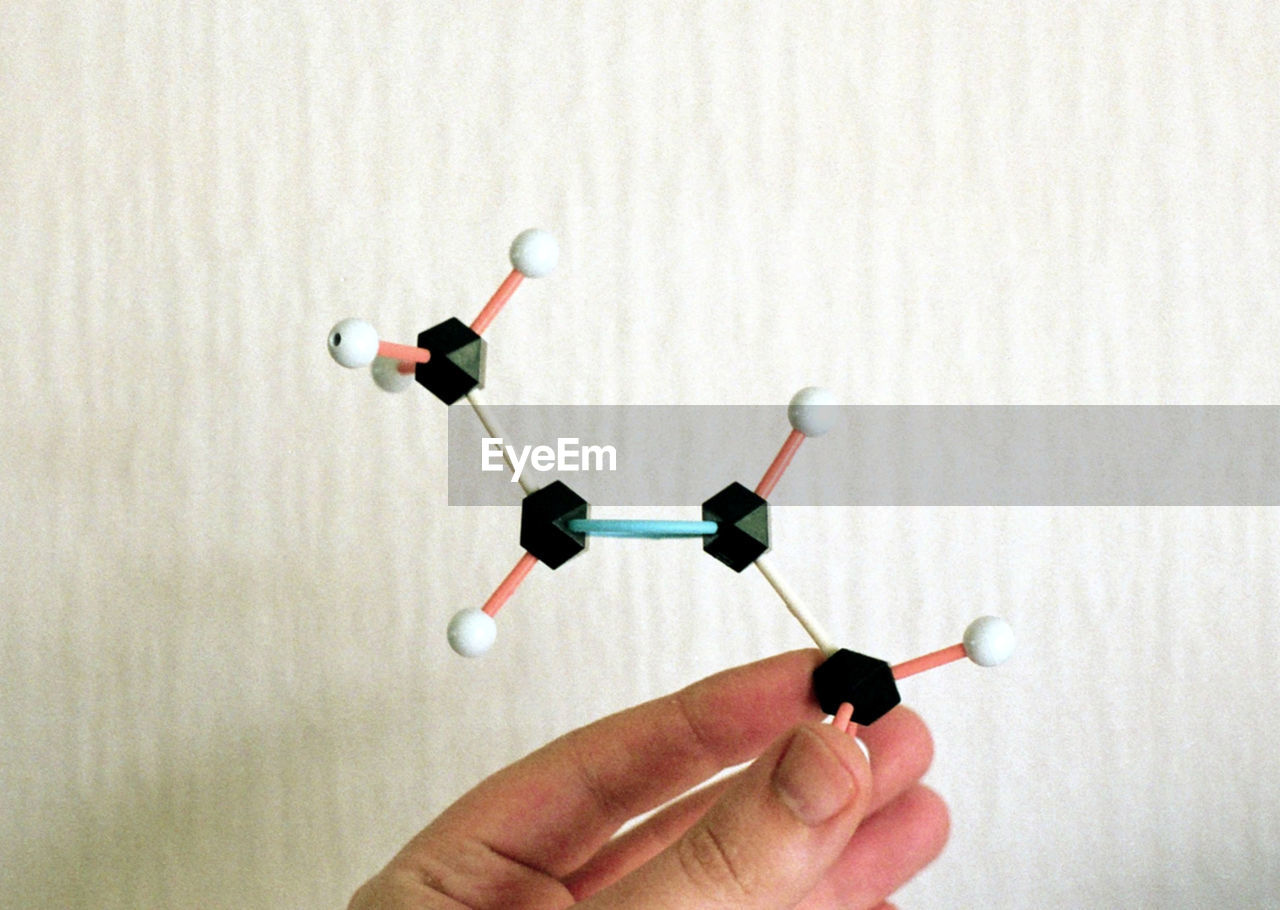 Close-up of hand holding molecule structure over white background