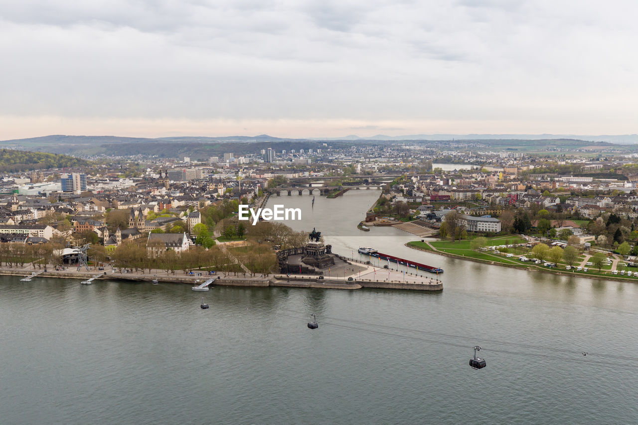 Aerial view of cityscape by river against sky