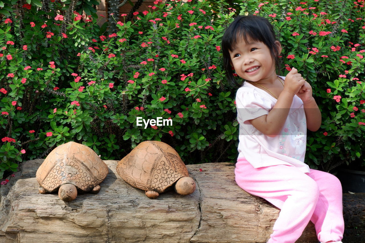 Cute girl sitting by tortoises against plants