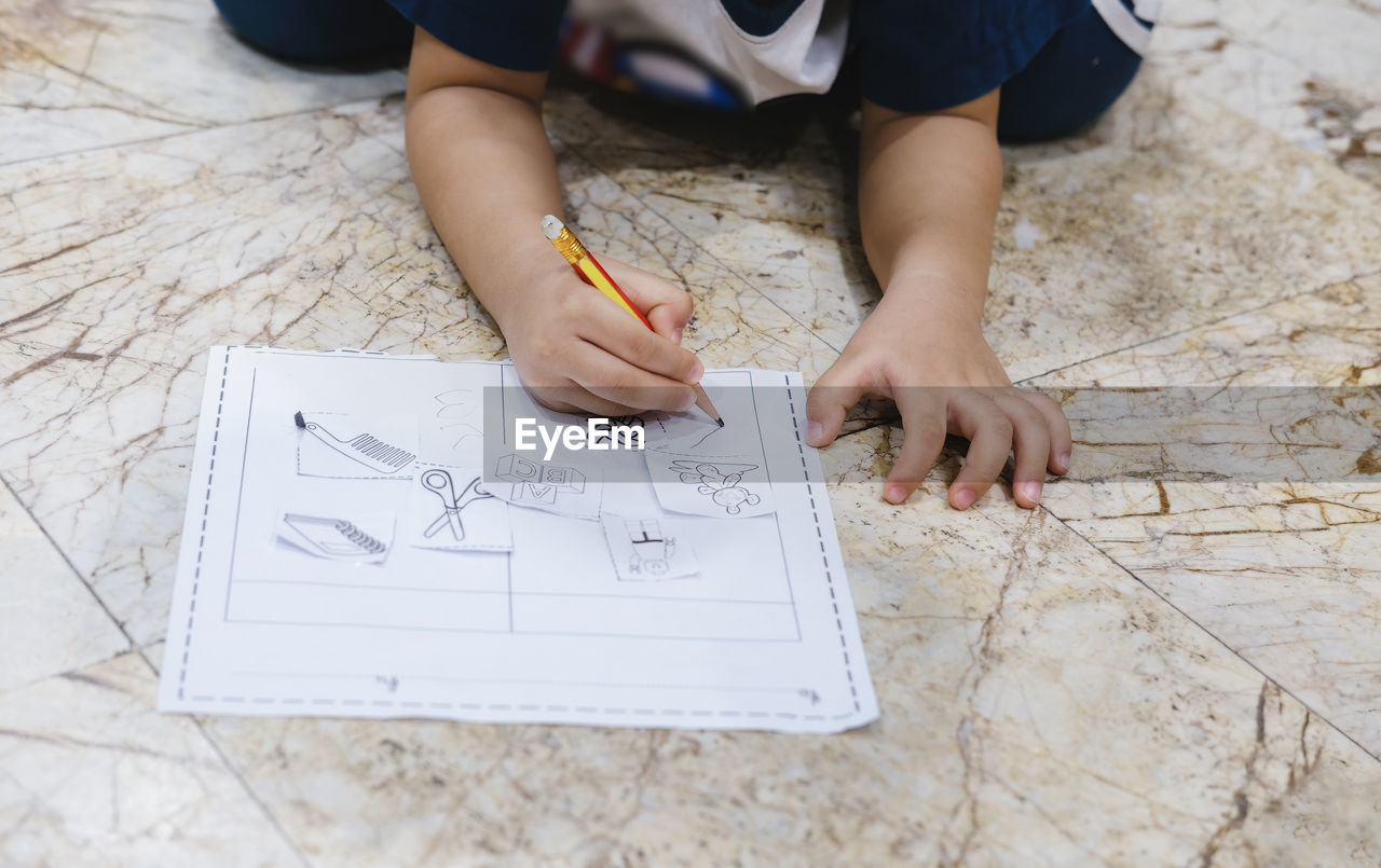 HIGH ANGLE VIEW OF CHILD ON PAPER WITH TEXT