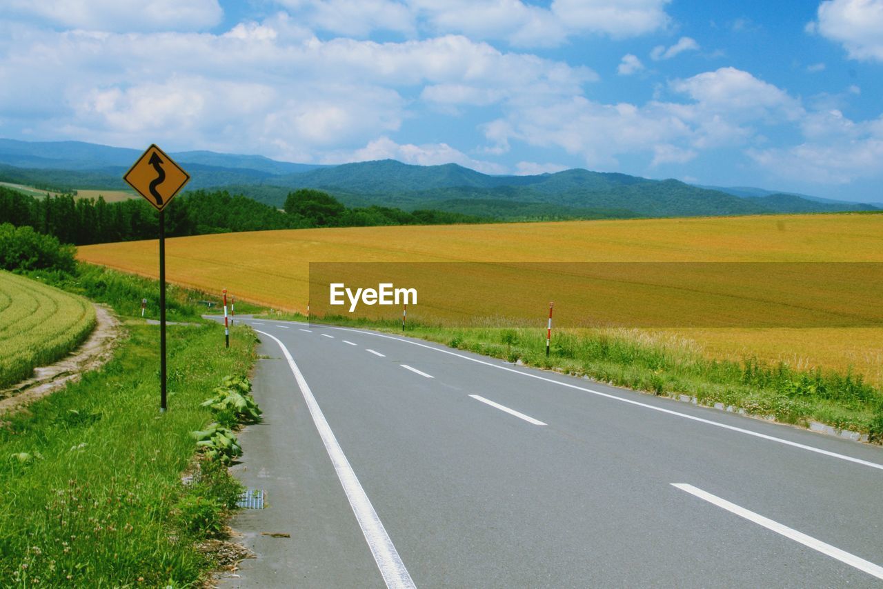 ROAD SIGN ON FIELD AGAINST SKY