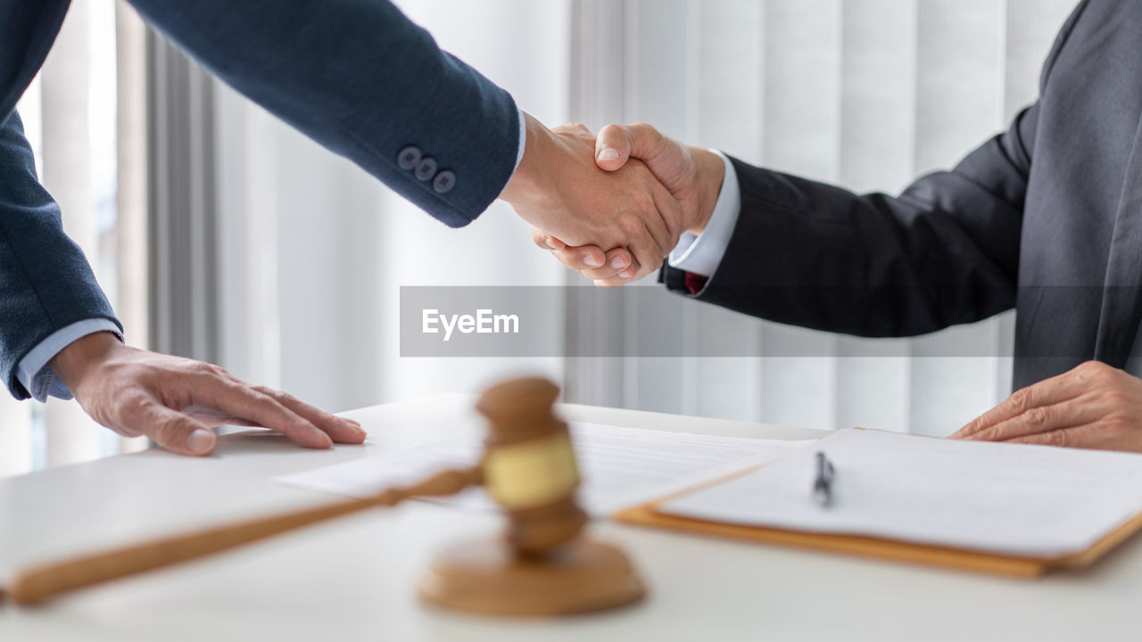 Midsection of lawyer shaking hands with client