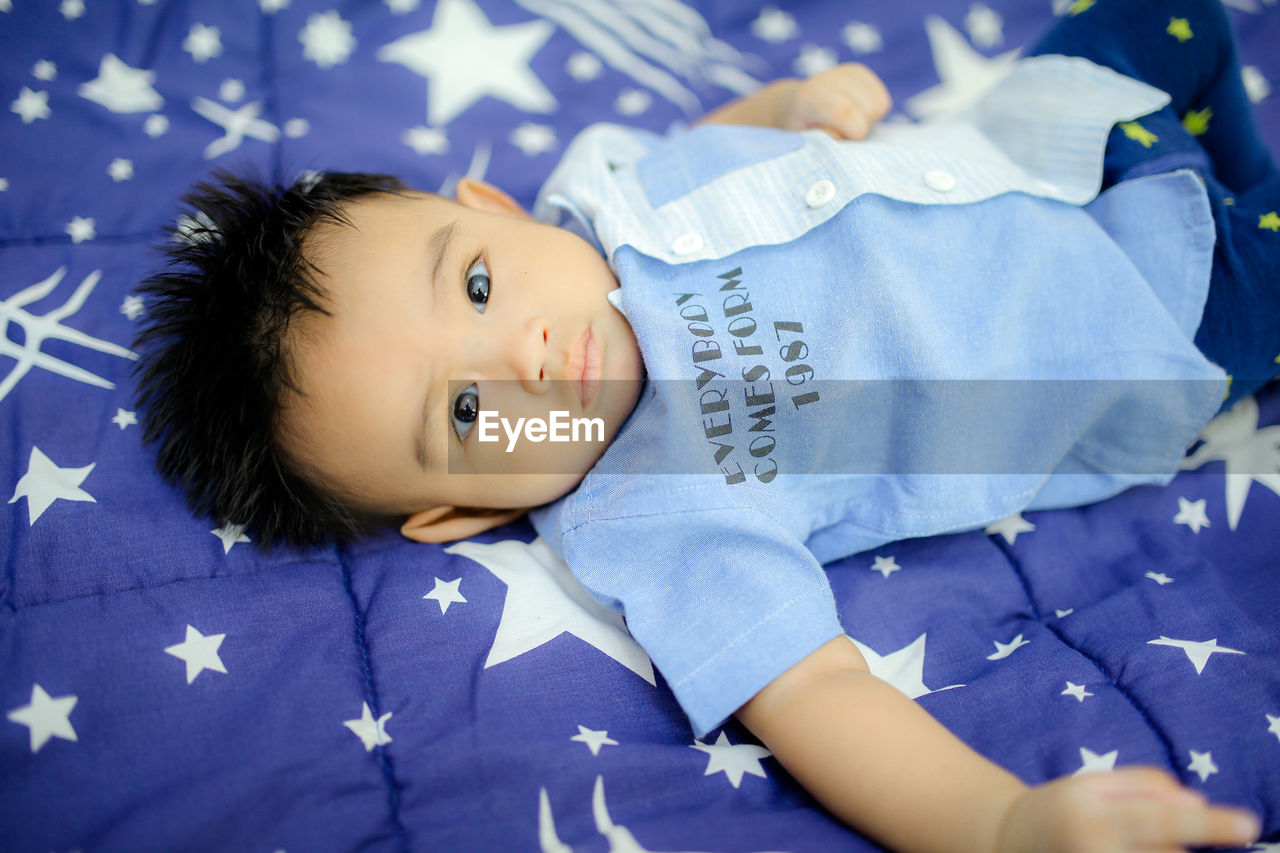 Portrait of cute baby girl lying on bed at home