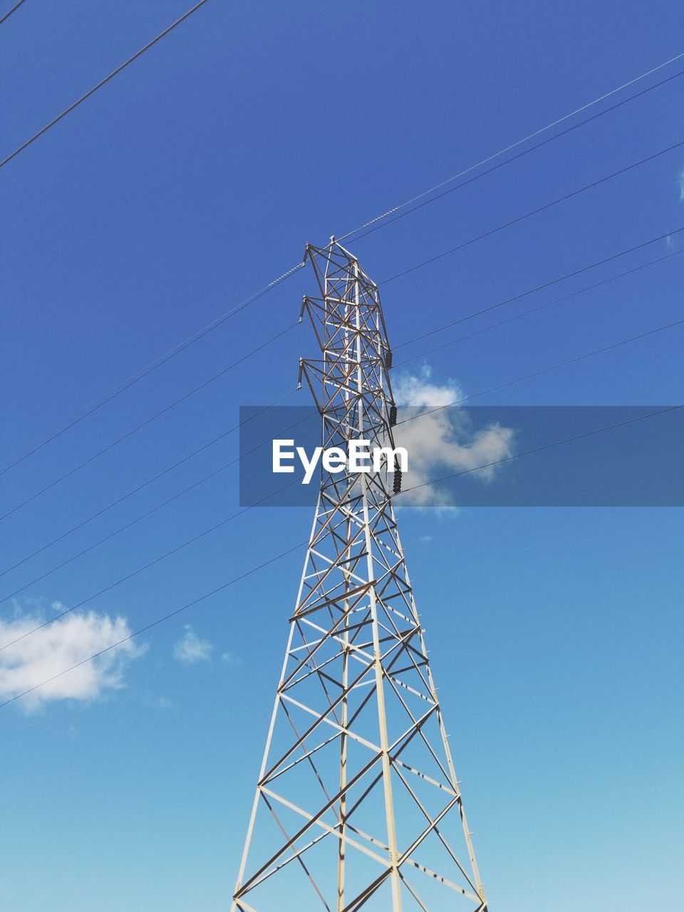 Low angle view of electricity pylon against blue sky