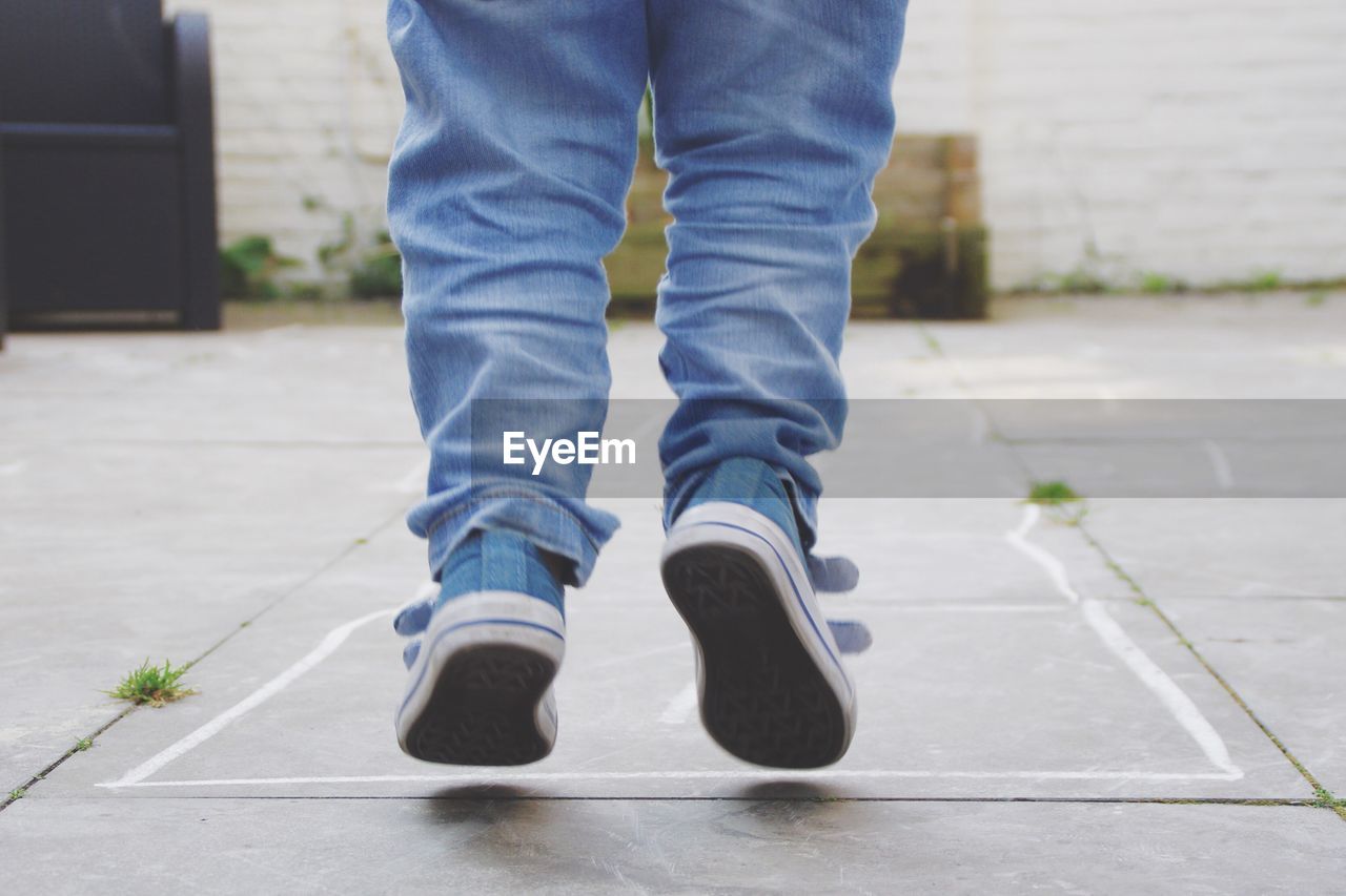 Low section of boy jumping on footpath