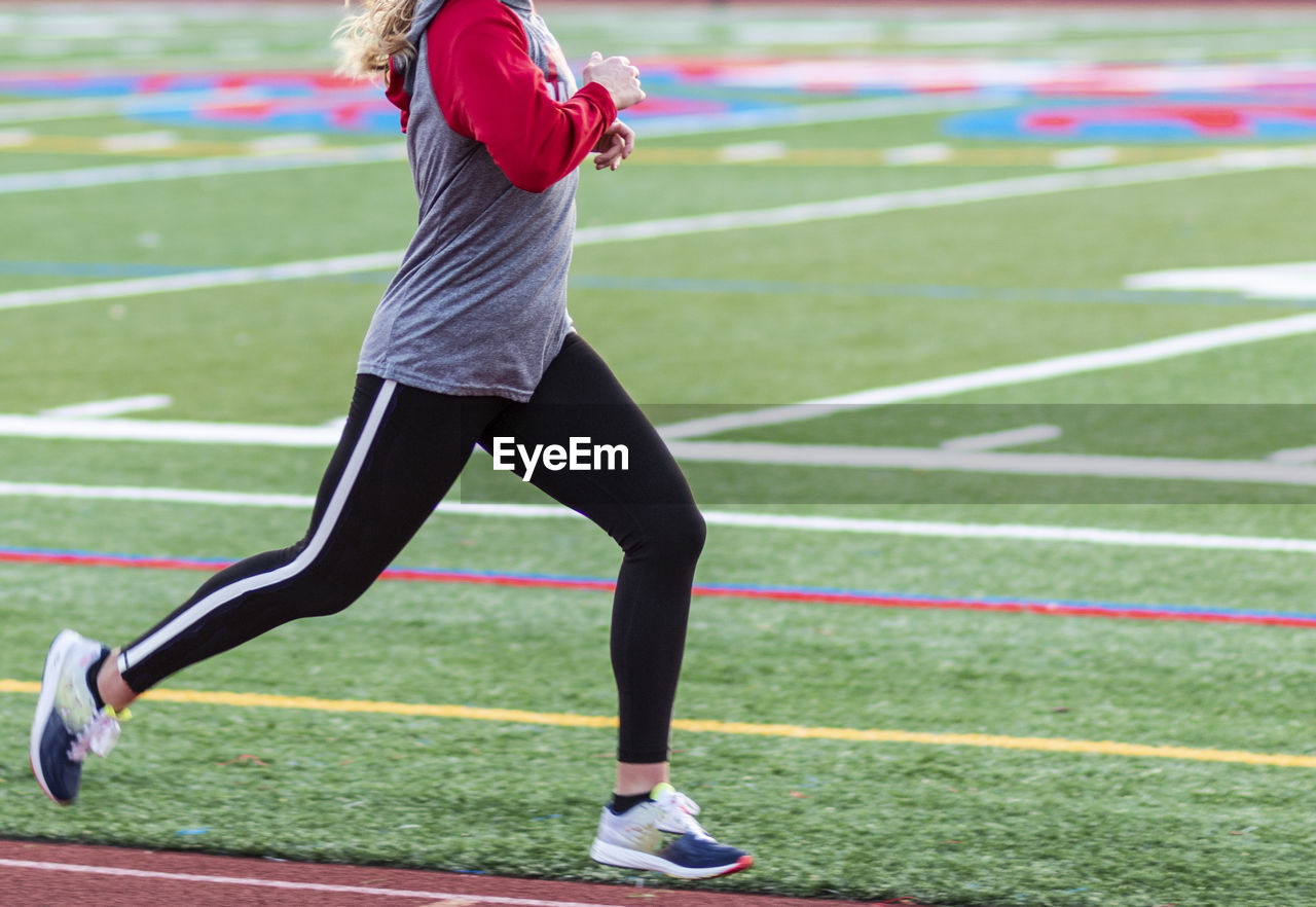 Midsection of woman running on field