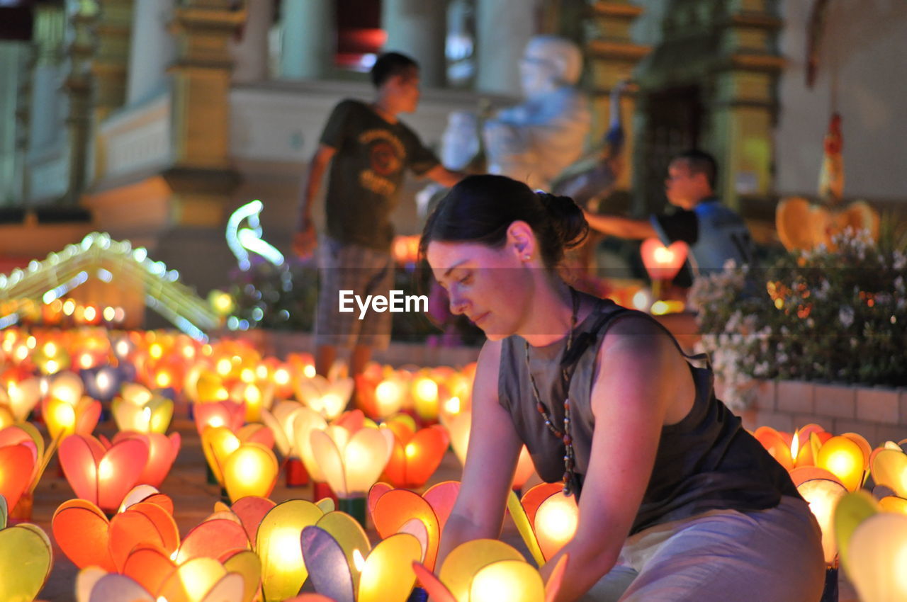 GROUP OF PEOPLE SITTING AT ILLUMINATED MARKET