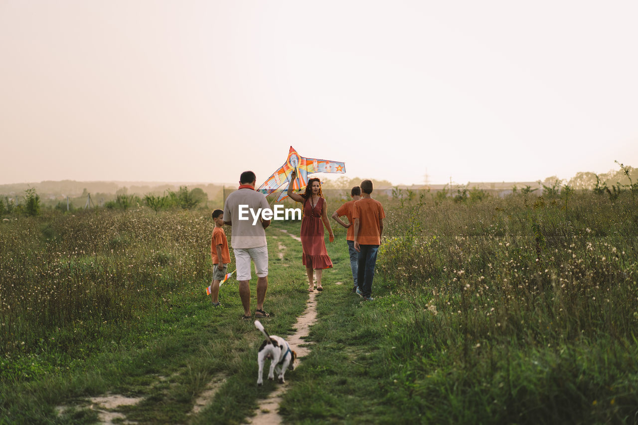 Happy family and children run on meadow with a kite in the summer on the nature.