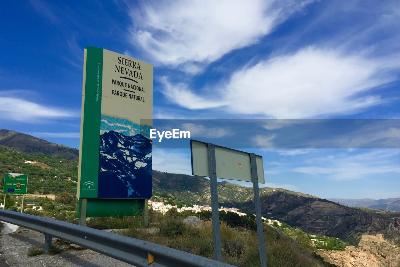 SIGNBOARD ON LANDSCAPE AGAINST CLOUDY SKY