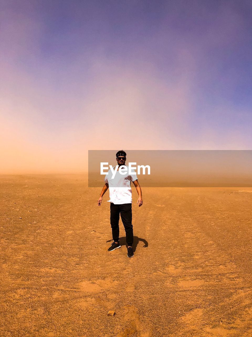 Full length portrait of man standing at desert against sky 