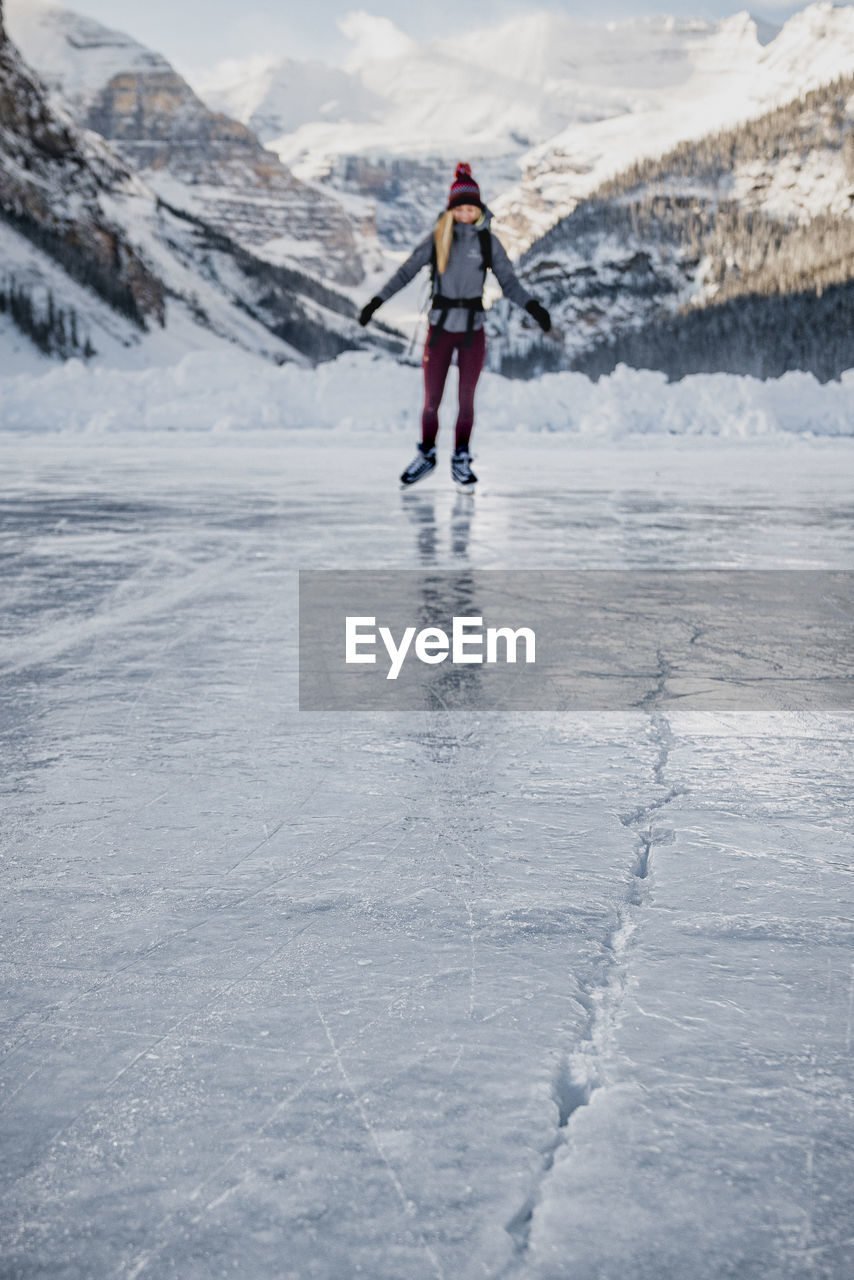 Young woman skating on frozen lake towards ice crack