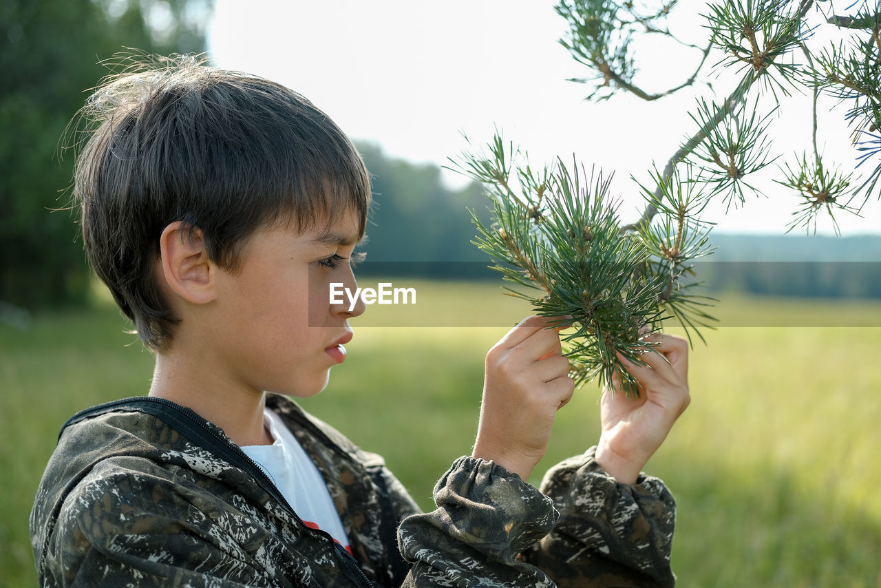 Side view of boy holding pine branch