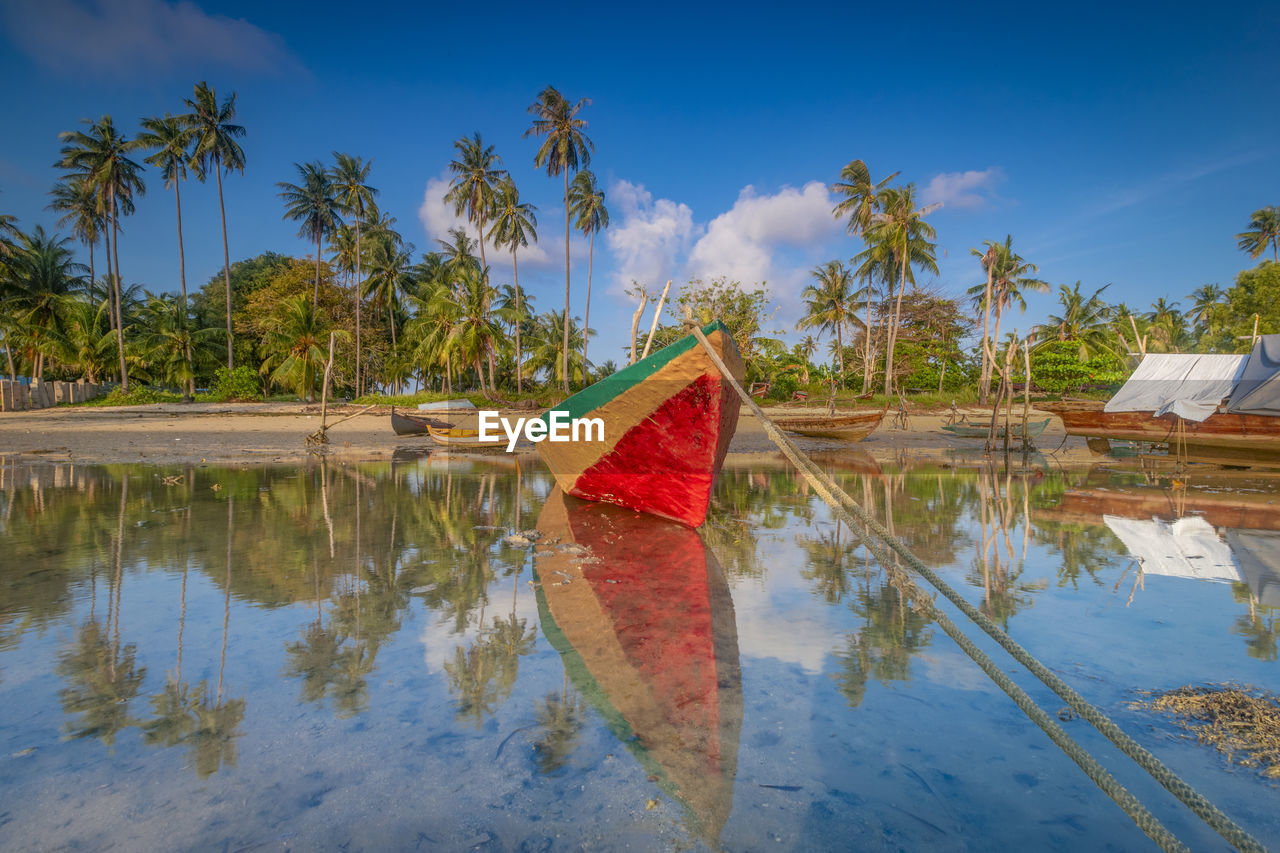 Boat moored on lake against blue sky