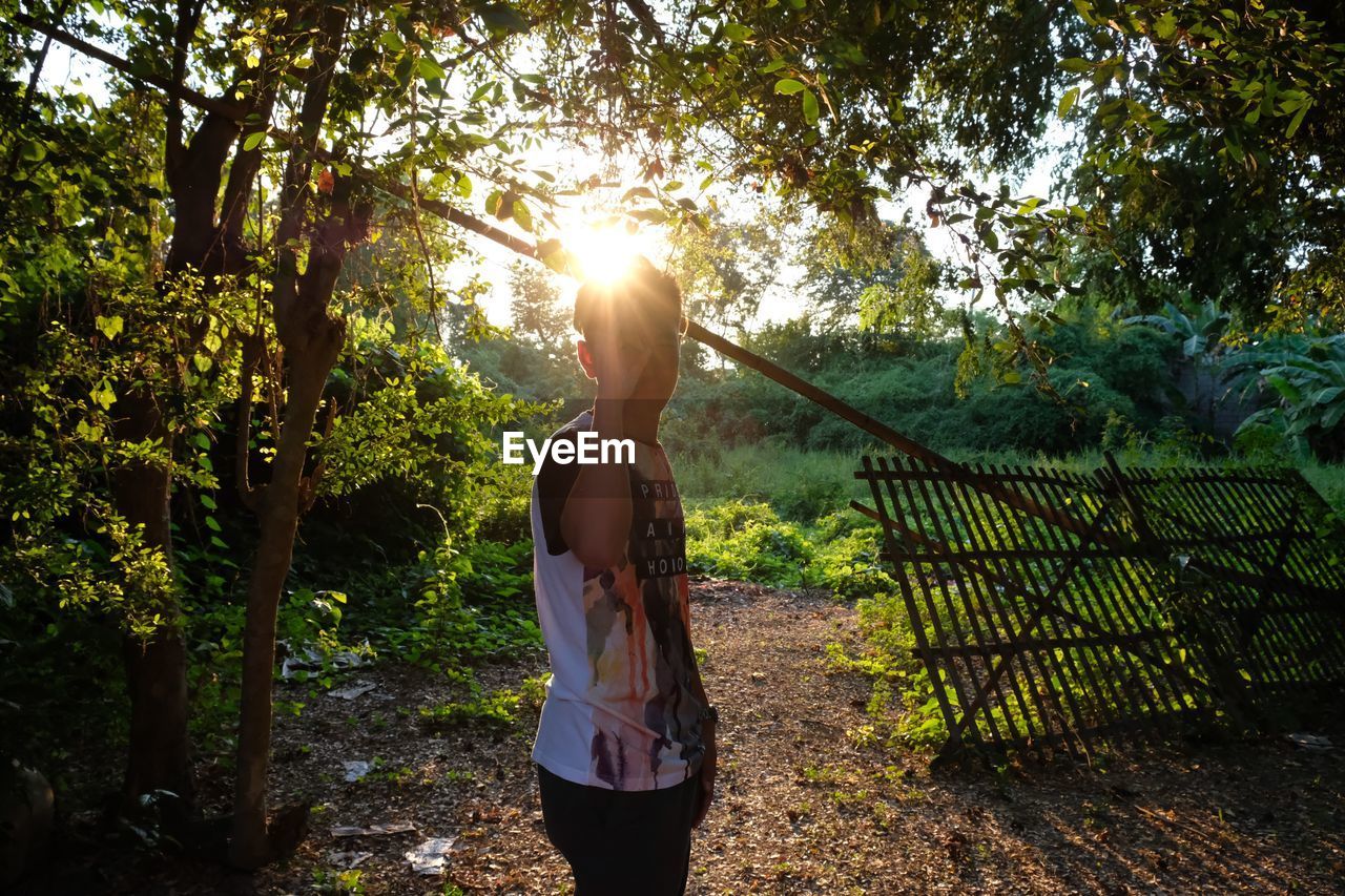 FULL LENGTH OF WOMAN STANDING BY TREES