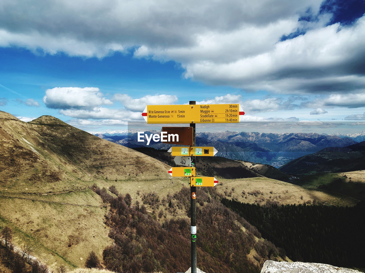 ROAD SIGN BY MOUNTAINS AGAINST SKY