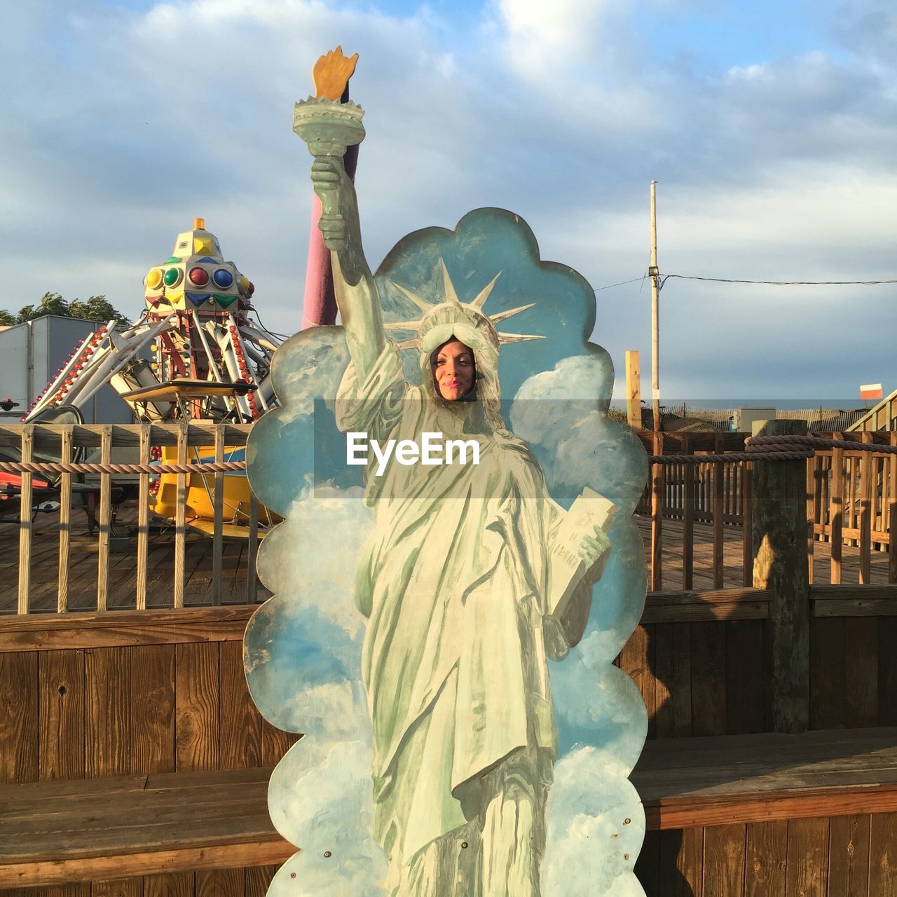 Woman behind statue of liberty replica at amusement park