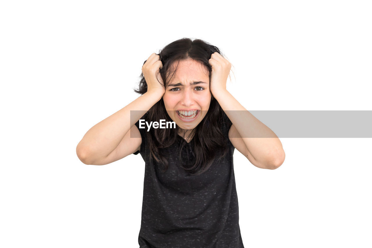 white background, adult, finger, one person, emotion, studio shot, cut out, portrait, negative emotion, indoors, women, frustration, t-shirt, looking at camera, young adult, hand, copy space, facial expression, anger, front view, casual clothing, female, displeased, clothing, shouting, waist up, positive emotion, happiness, arm, emotional stress, black, person, gesturing, human face, smiling, relaxation, communication, hairstyle, furious, arms raised, lifestyles, hand in hair