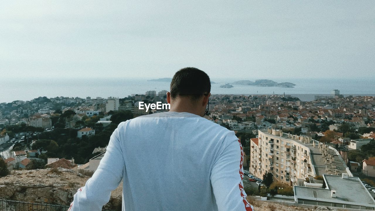 Rear view of man looking at townscape against sky