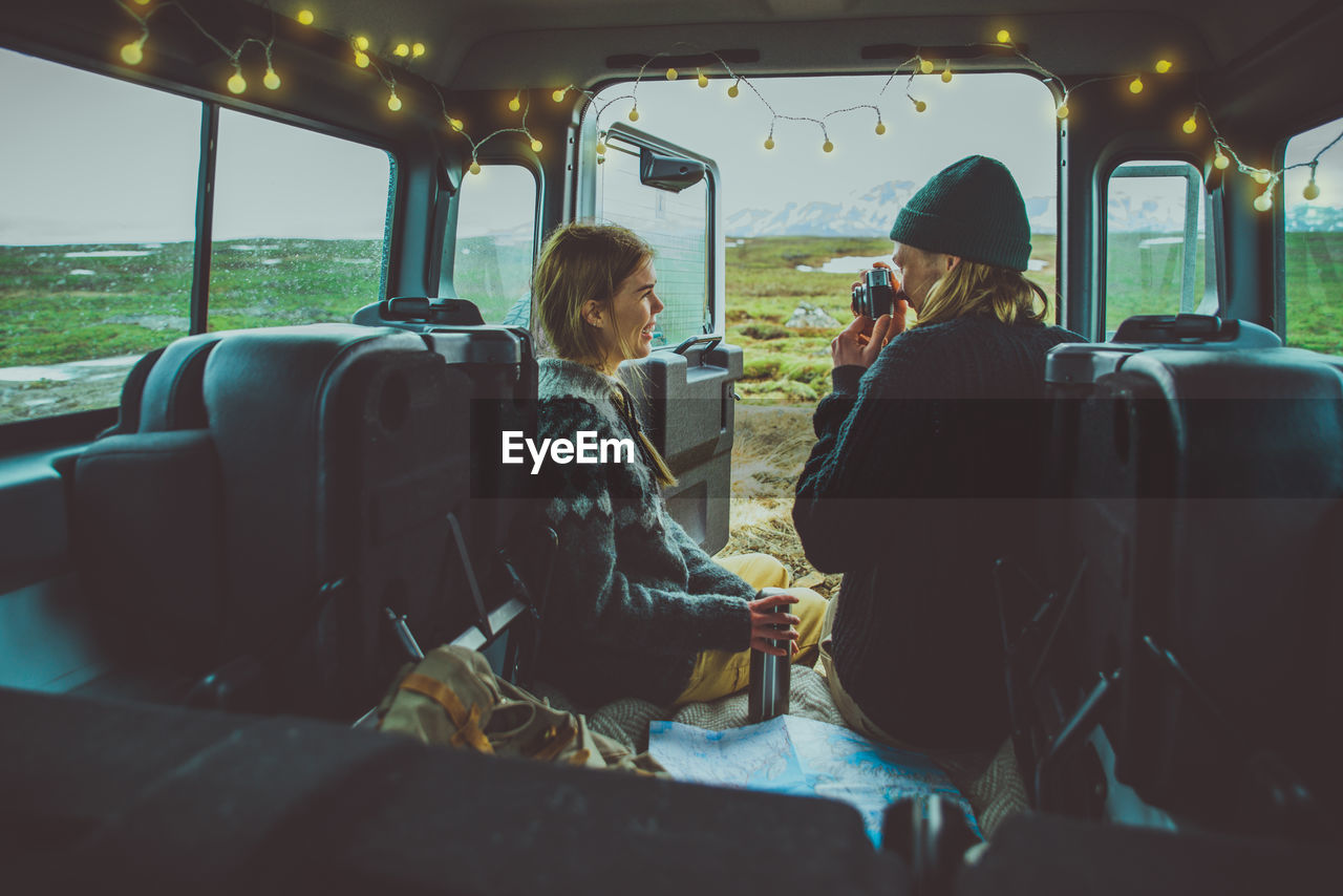 REAR VIEW OF COUPLE SITTING IN BUS