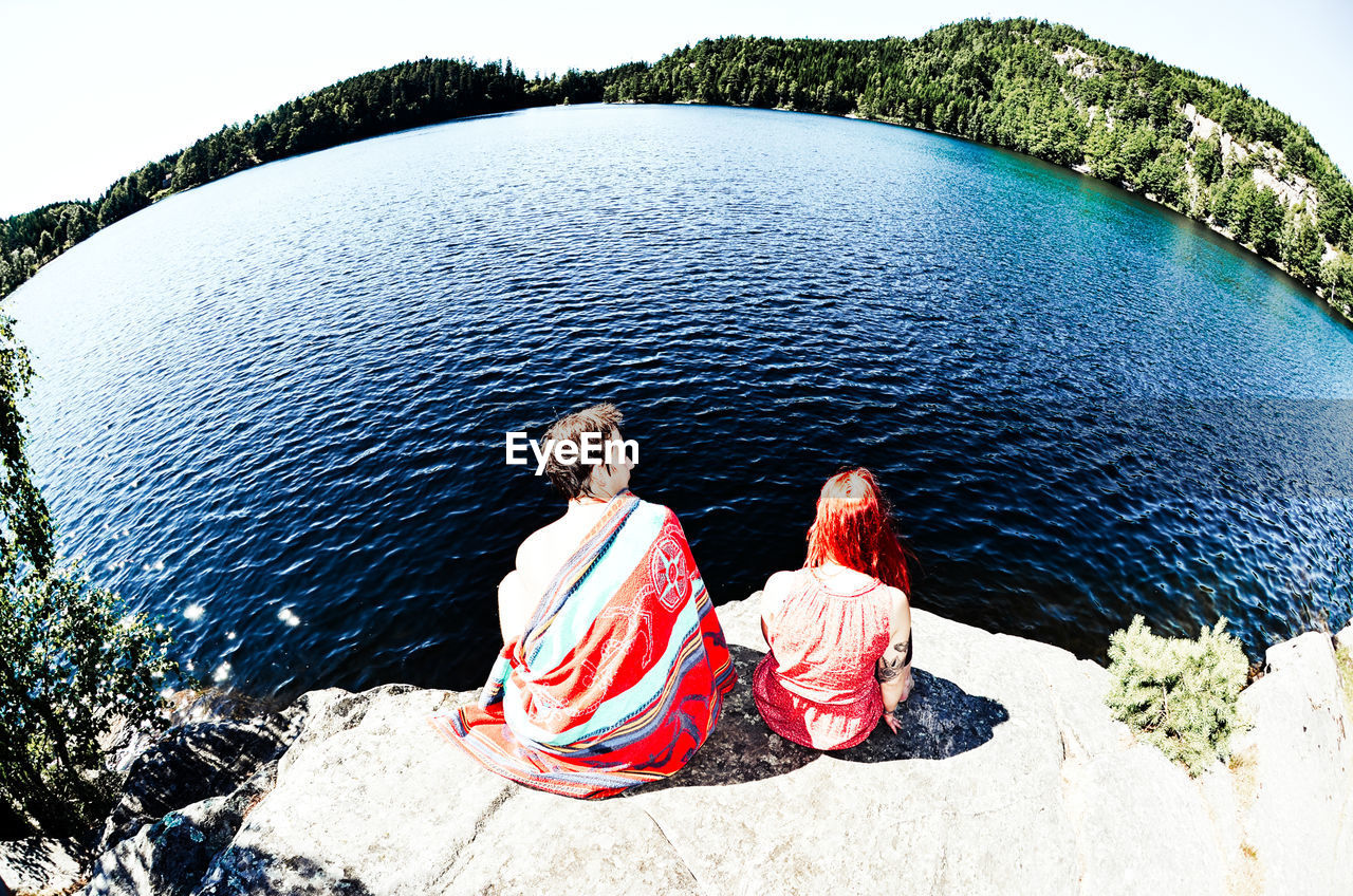 Rear view of young couple sitting on rock