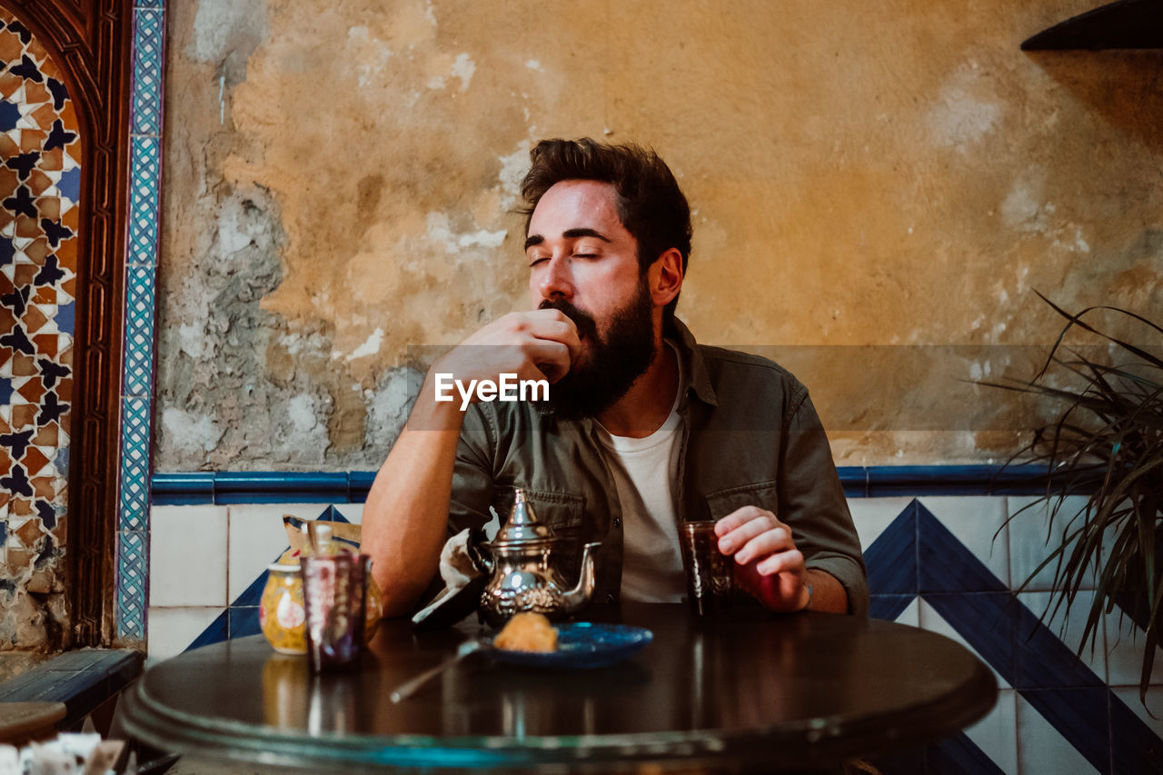 Man eating food while sitting on table in restaurant