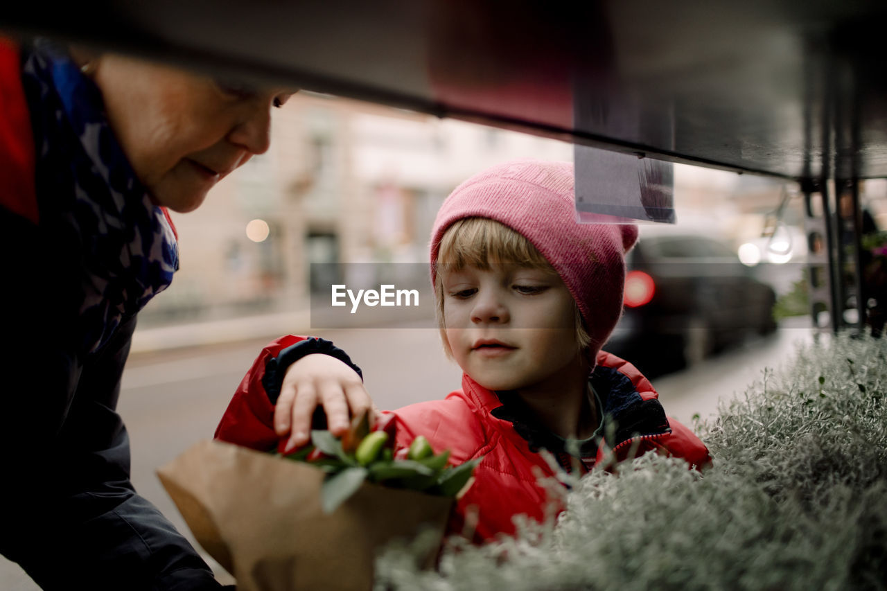 Senior woman buying plants with grandson in city