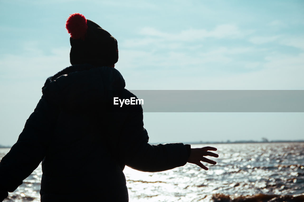 Child with winter clothing near the sea