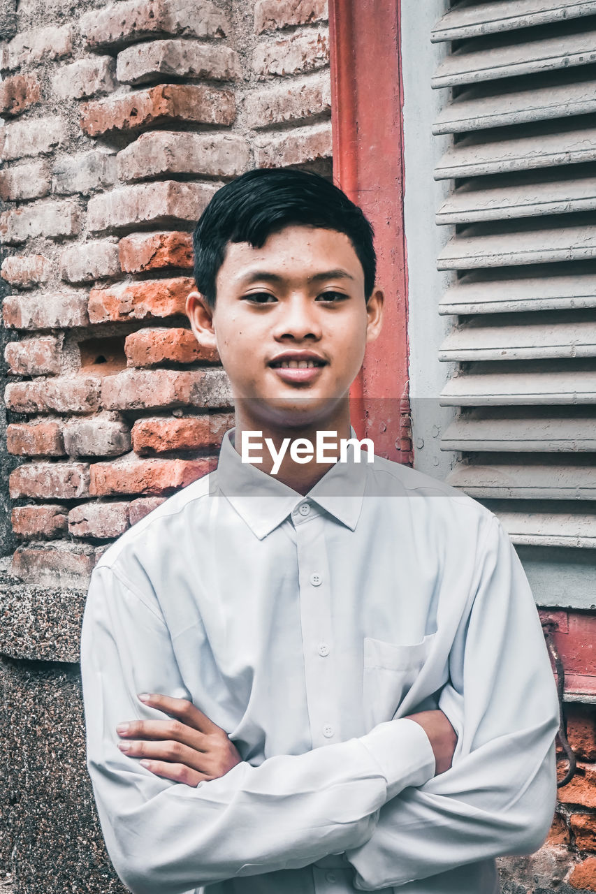 PORTRAIT OF YOUNG MAN AGAINST WALL