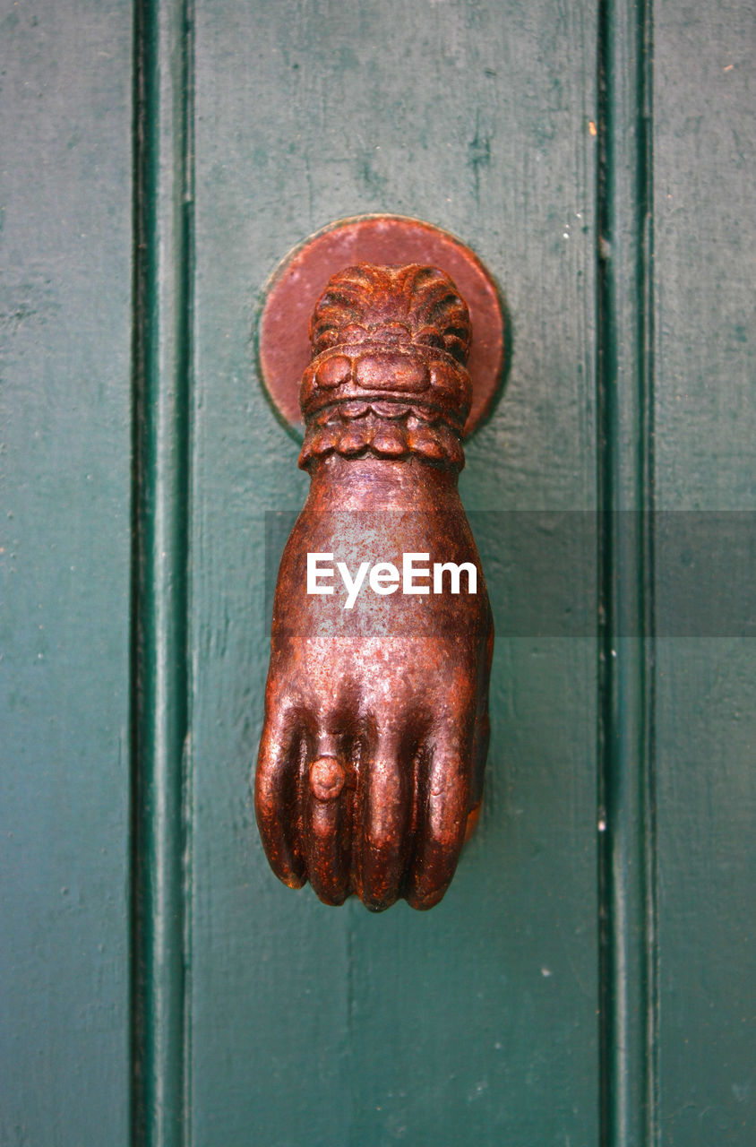 Close-up of rusty antique knocker on metal door