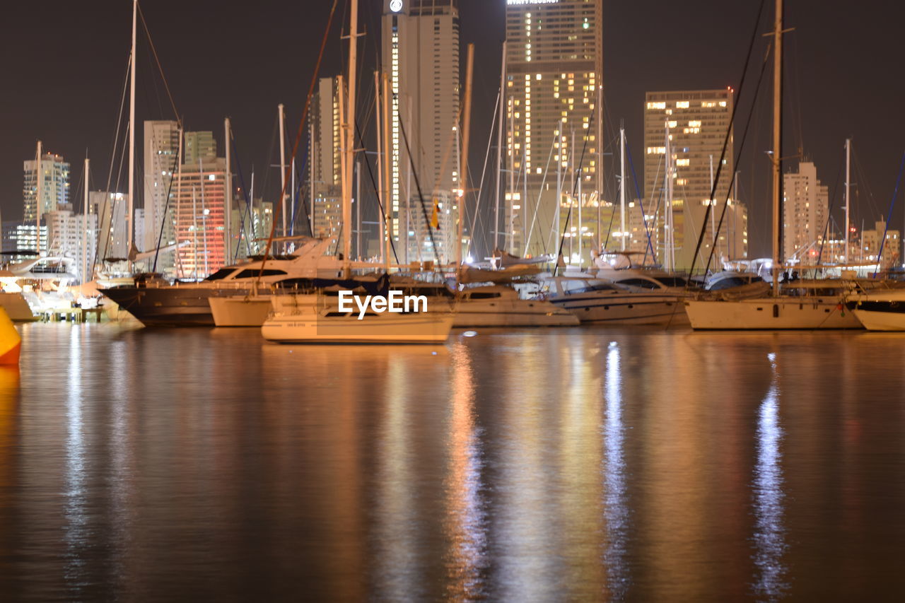 Boats moored in harbor at night