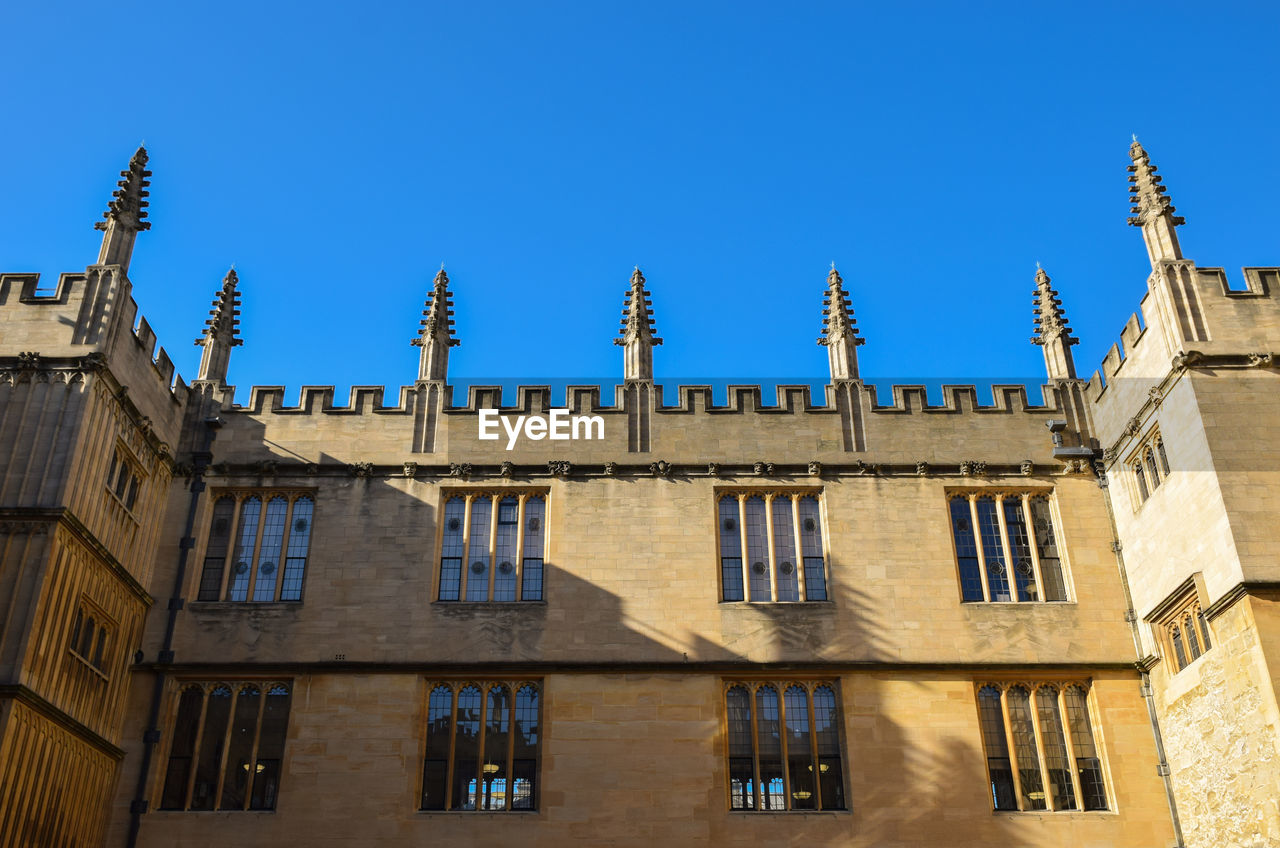 Low angle view of historic university against clear blue sky