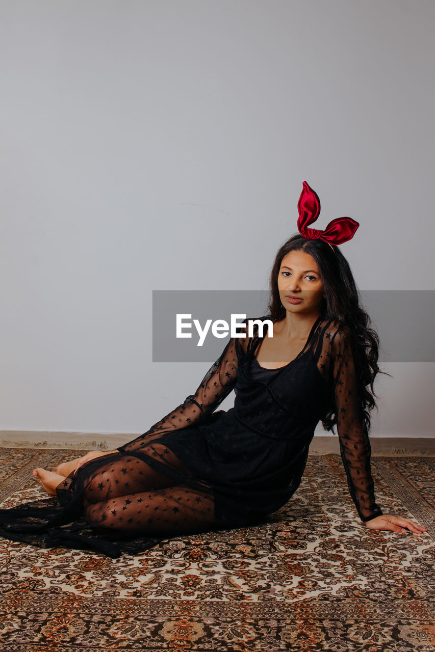 Young woman with red bow looking down. easter themed fashion photography. hair accessory.